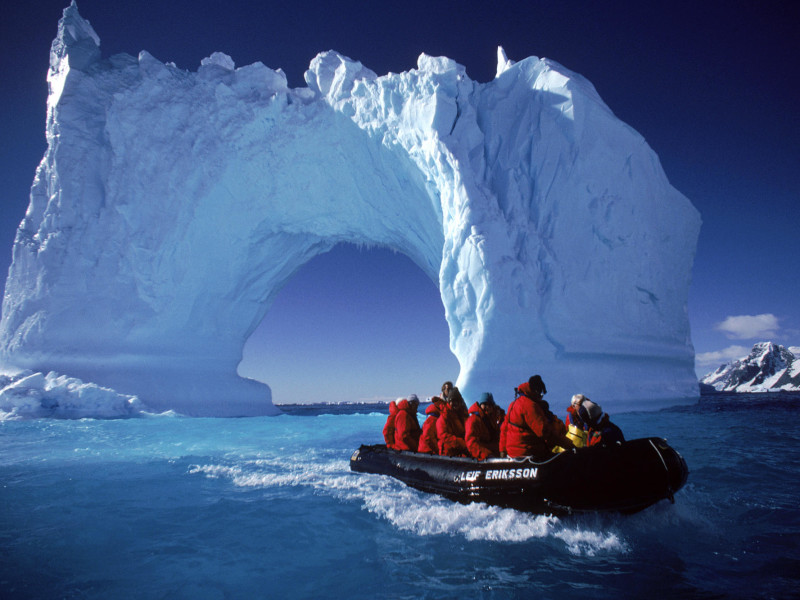 Boating By An Iceberg Arch Near Yalour Islands, Antarctica.